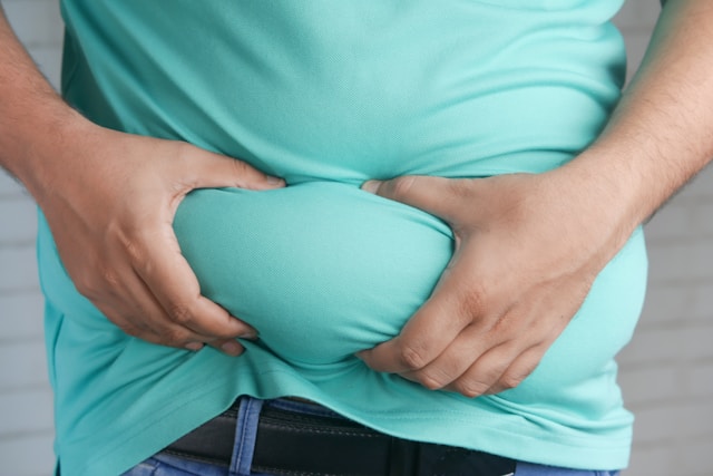 Ohne Diät abnehmen - Mann fasst sich an seinen Bauch